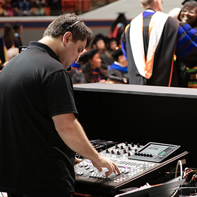 An SHSU Online Media Innovation team member operating equipment for a commencement ceremony